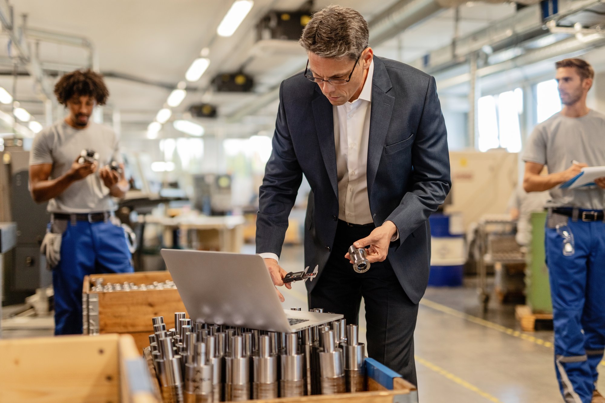 factory-manager-reading-instructions-computer-while-checking-measurements-steel-bolt-industrial-building-manual-workers-are-background