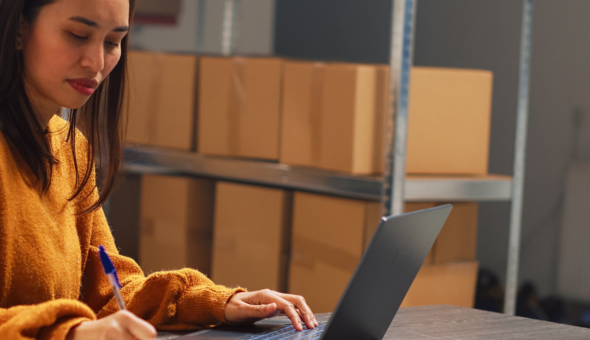 female-entrepreneur-taking-notes-papers-pc-working-warehouse-inventory-shipping-logistics-young-adult-checking-products-boxes-before-distribution-handheld-2