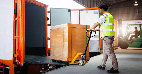 Man uses a dolly to load freight into a truck 