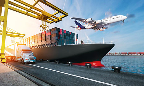 Photo of a shipping harbor showing a truck, shipping vessel, and airplane