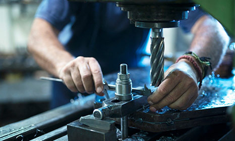 Photo of a man in a fabrication shop using a drill